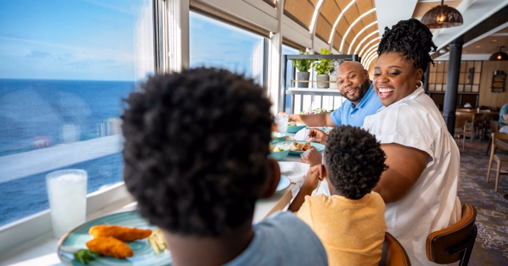 Família almoçando no Marceline Market, com vista para o mar, em navio da Disney Cruise Line