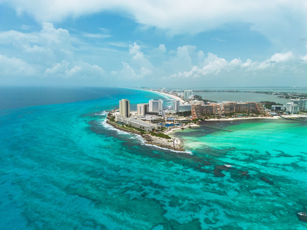 Vista aérea da Zona Hotelera de Cancún, com mar azul-turquesa e recifes no Caribe mexicano.